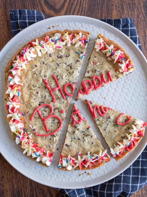large round chocolate chip cookie cake with birthday decorations sliced