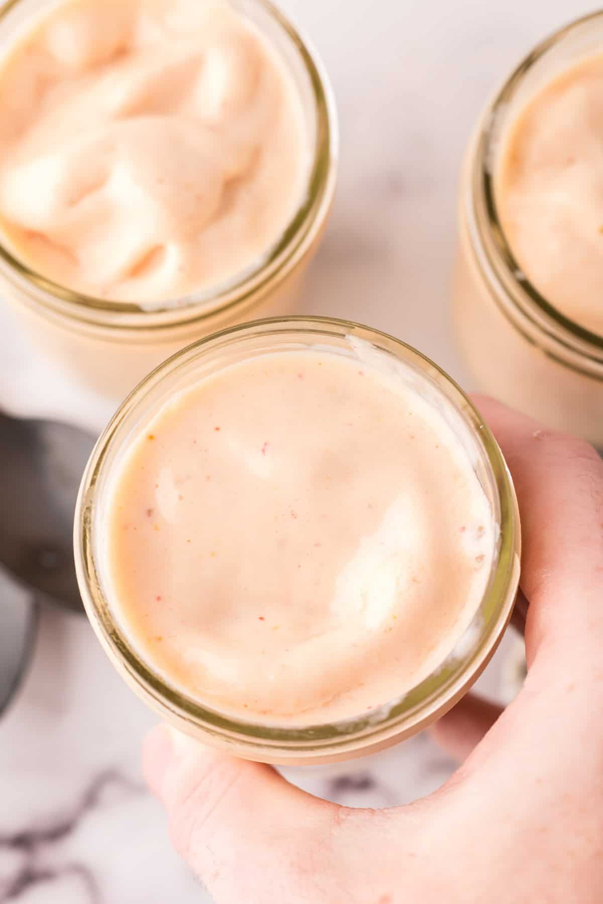 POV hand holding a small mason jar with a smoothie.