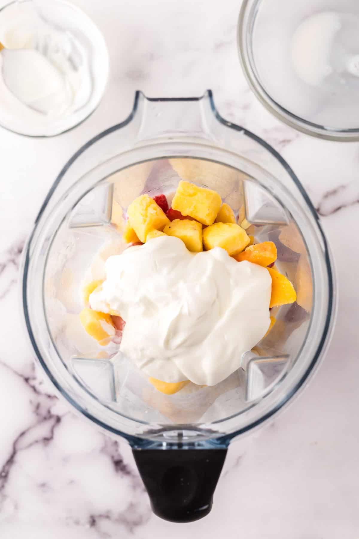 fresh fruit and yogurt in a blender for a smoothie recipe.