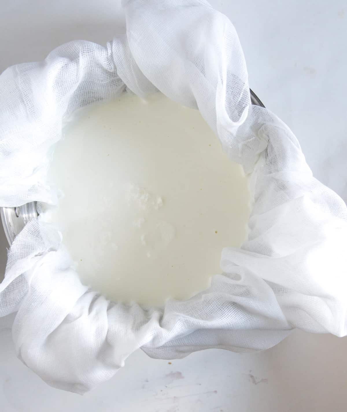 Slow cooker yogurt is an easy, healthy and inexpensive way to make homemade yogurt without a yogurt maker. Top view of yogurt straining through cheese cloths.