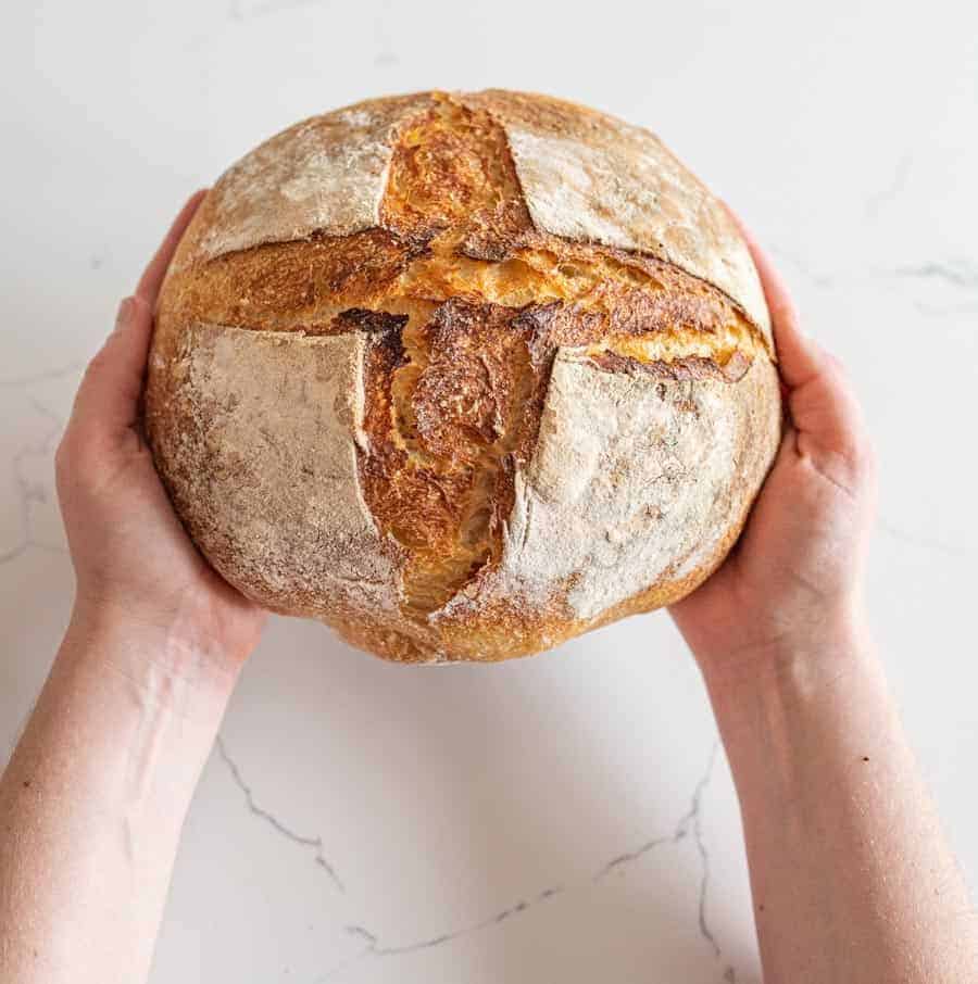 woman holding a loaf of sourdough bread.